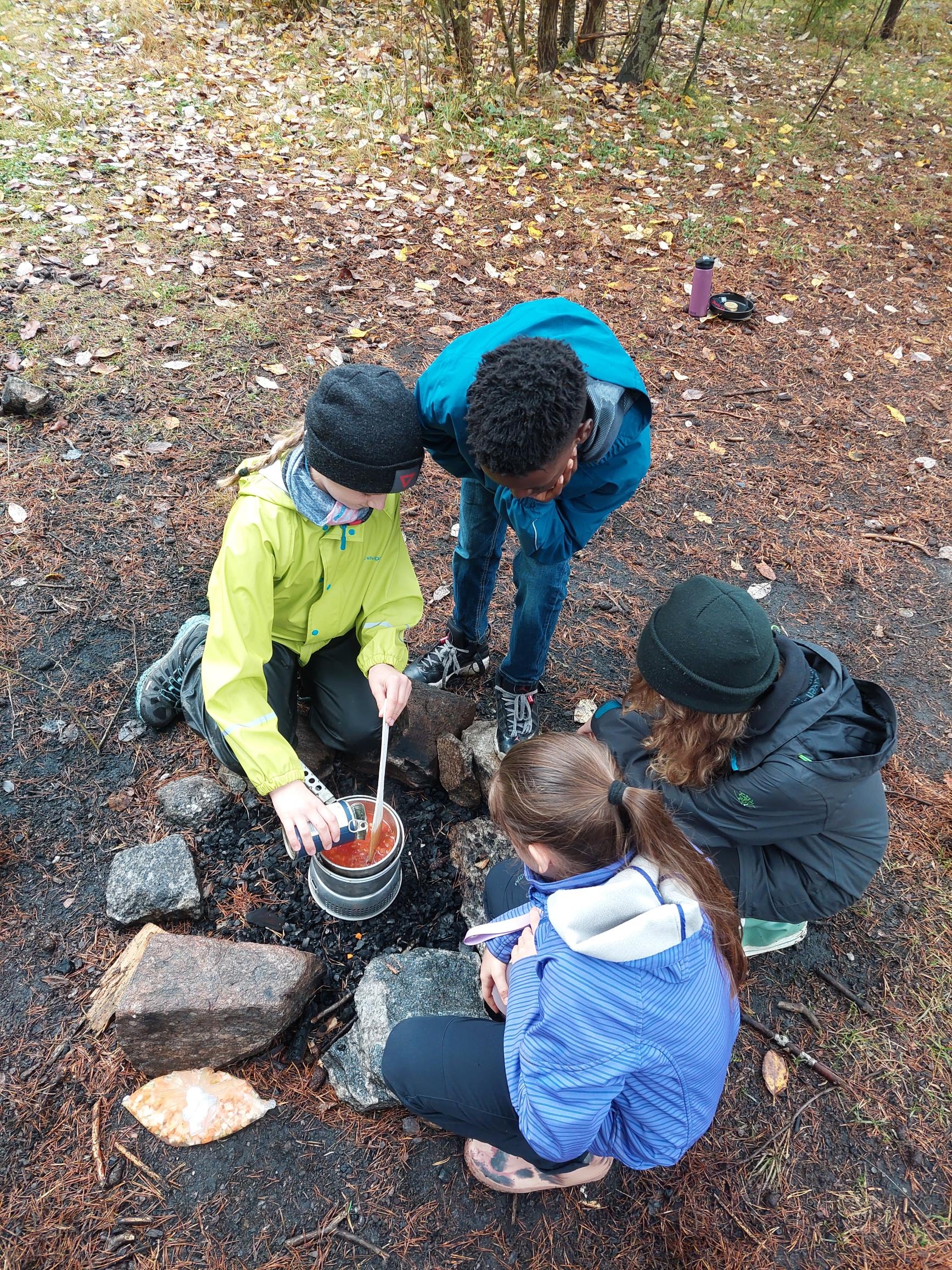 Barn som lager mat ute på primus