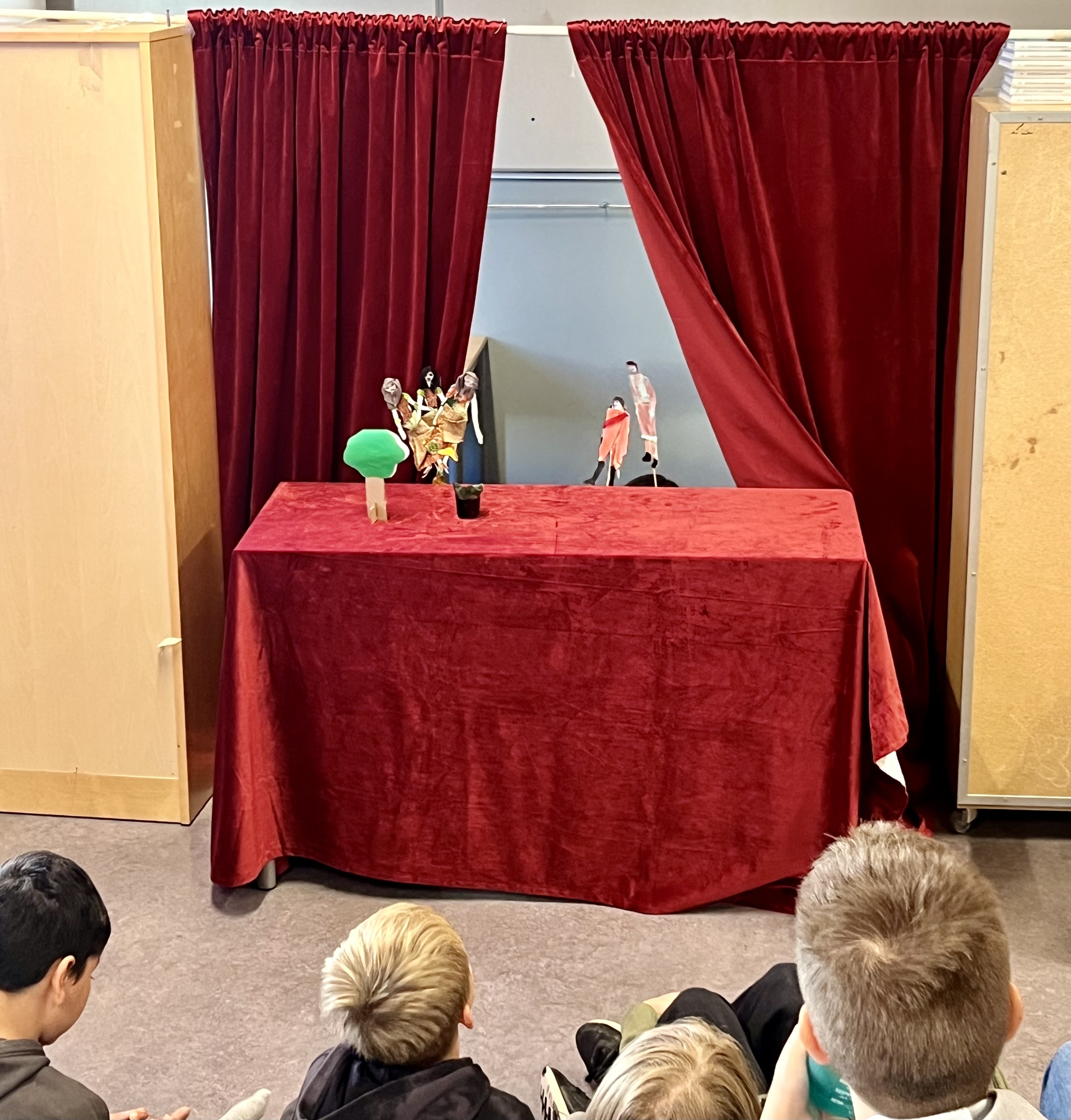 En gruppe mennesker som sitter foran en scene med røde gardiner
