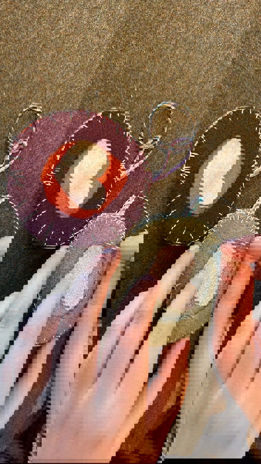 Foto: Line Schibstad et par hender som syr en hjerteformet pynt