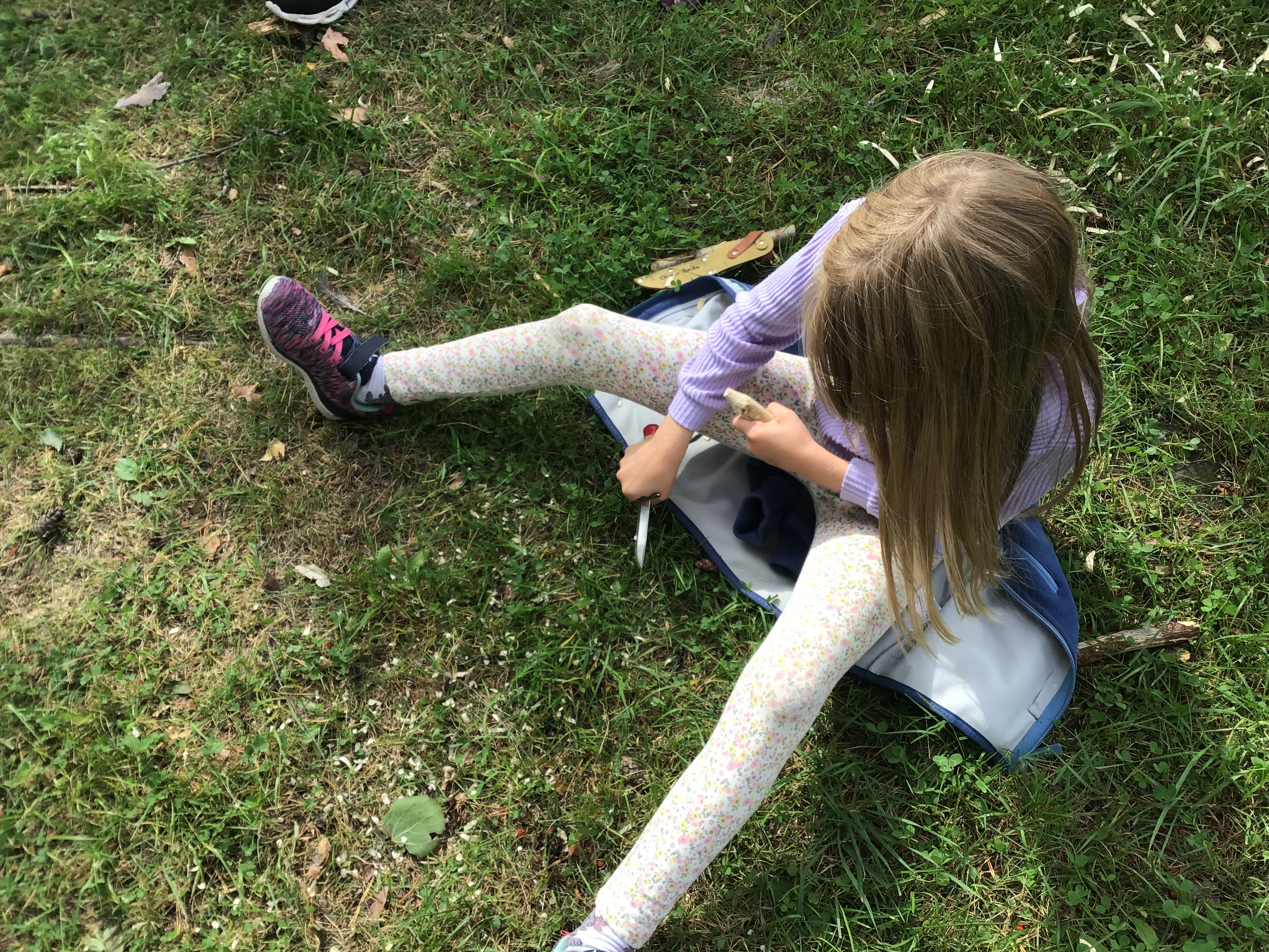 Jente som sitter på gresset og spikker